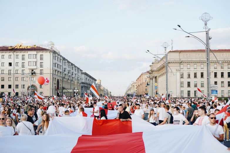 a crowd of people holding a large red and white flag, by Julia Pishtar, pexels contest winner, president of belorussia, square, polaeized light, summer street