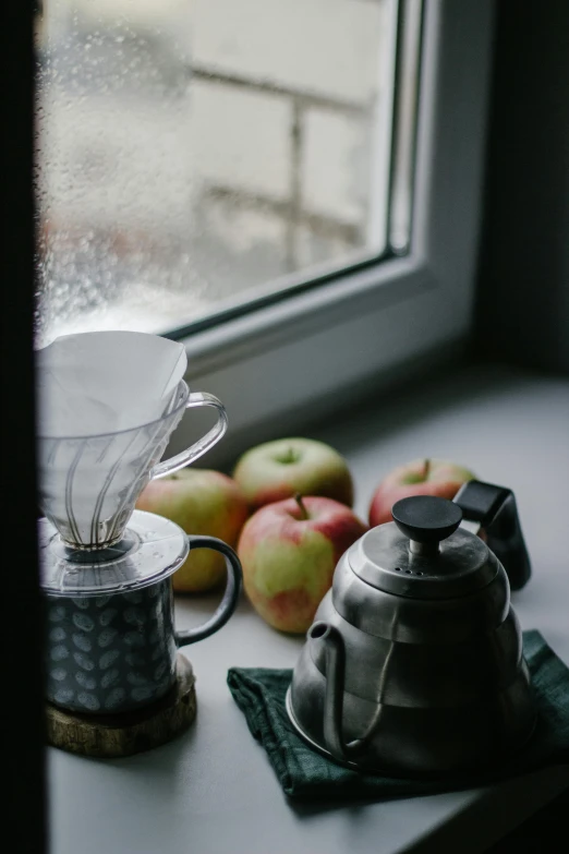 a coffee pot sitting on top of a window sill, a still life, unsplash contest winner, apples, rainy and foggy, coffee cups, stainless steel
