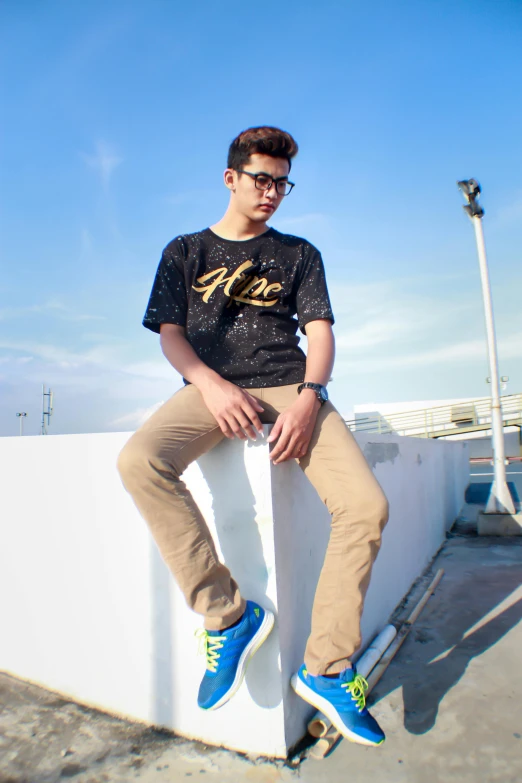 a man sitting on a wall with a skateboard, inspired by Aleksander Gine, pexels contest winner, wearing pants and a t-shirt, avatar image, blue sky, kyza saleem