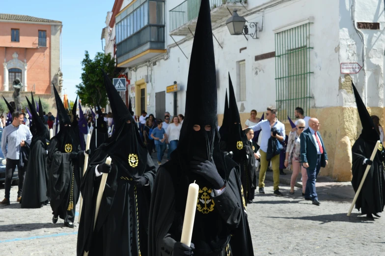 a group of people dressed in black walking down a street, by Pedro Álvarez Castelló, pexels contest winner, antipodeans, wearing traditional garb, holding a spear, white wearing, parce sepulto