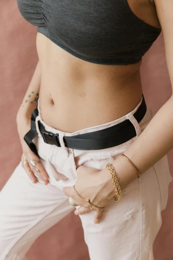 a woman standing with her hands in her pockets, by Nina Hamnett, trending on pexels, silk belt, sport bra, black white pastel pink, zoomed out view