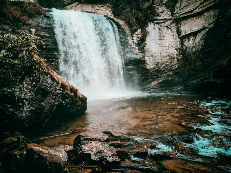 a waterfall in the middle of a forest, pexels contest winner, brown water, vsco film grain, thumbnail, deep clear pools of water