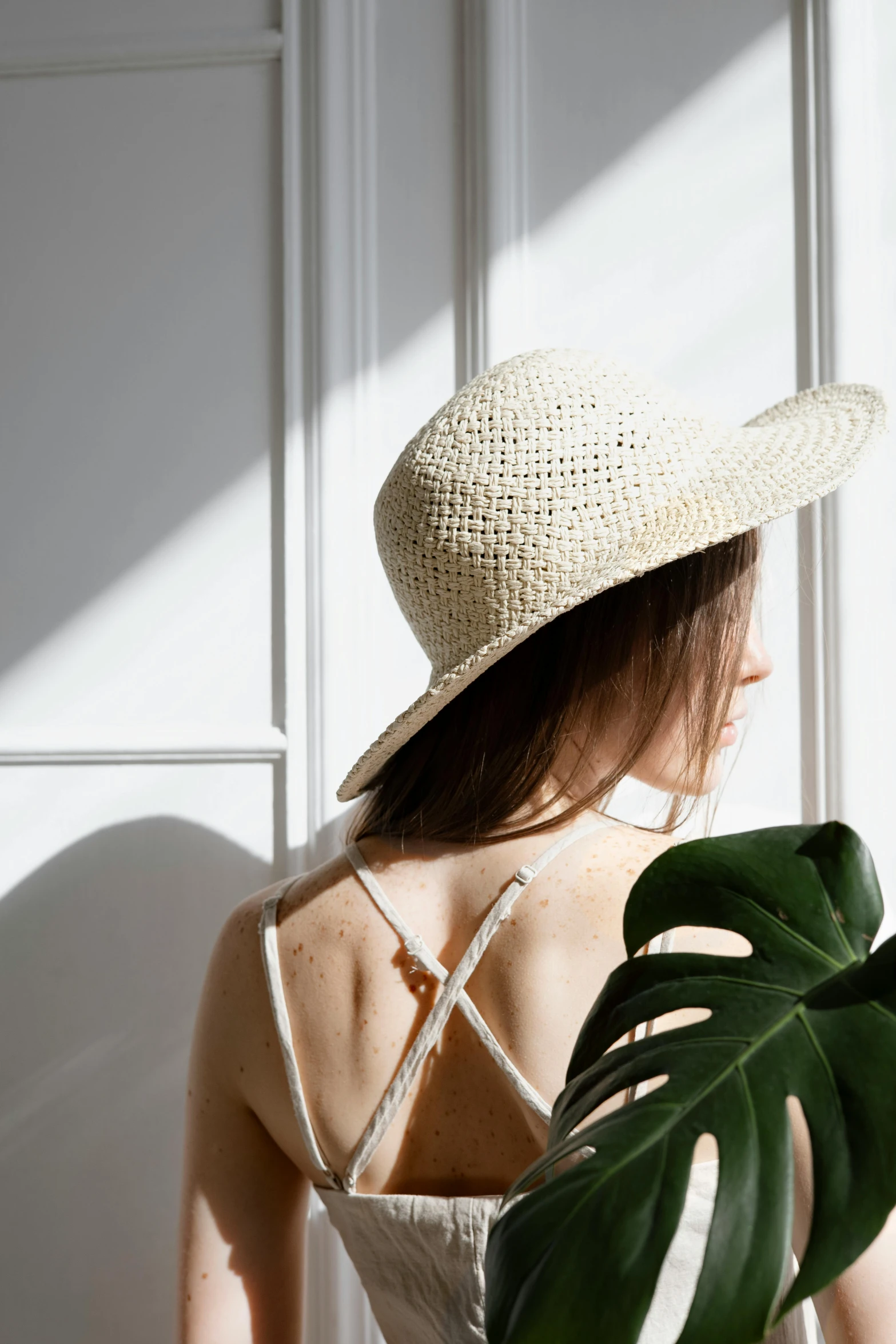 a woman in a straw hat holding a plant, by Maud Naftel, pexels contest winner, minimalism, arched back, light glare, bralette, detailed white