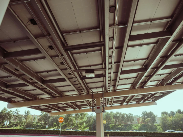 a parking lot filled with lots of parked cars, a digital rendering, by Carey Morris, unsplash, photorealism, sky made of ceiling panels, webdesign icon for solar carport, bending down slightly, dark cables hanging from ceiling