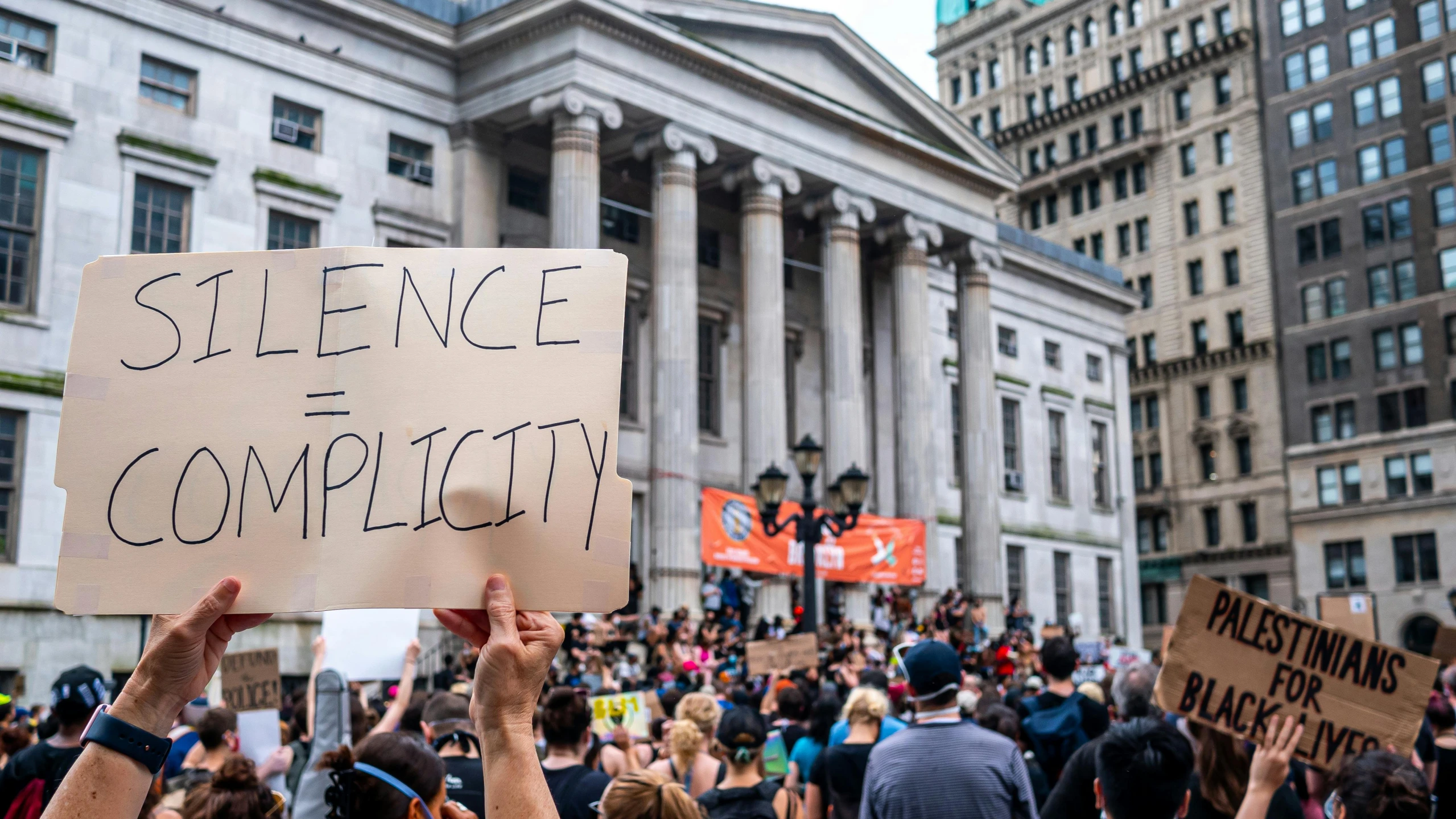 a group of people holding signs in front of a building, by Benjamin Block, pexels, renaissance, attacking nyc, balancing the equation, panel of black, a person standing in front of a