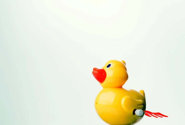 a yellow rubber duck sitting on top of a table, an album cover, unsplash, minimalism, plastic toy, puppet on a string, low quality photo, lipstick