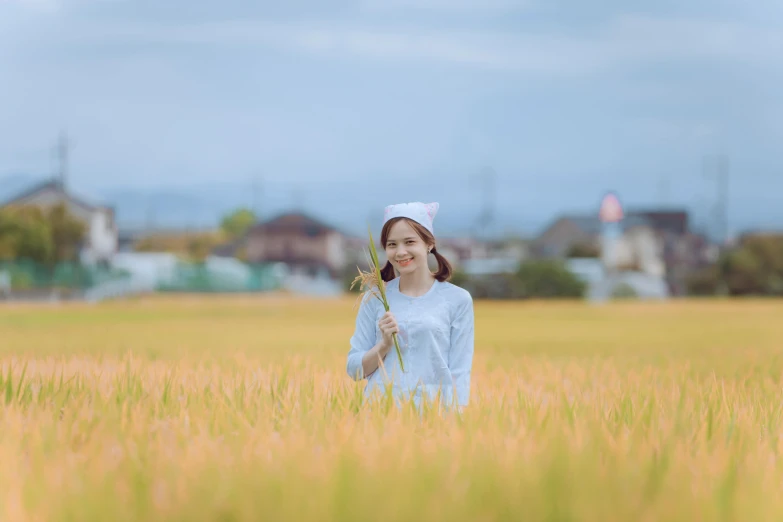 a woman standing in a field holding a flower, by Sengai, unsplash, avatar image, japanese rural town, 8 k image, wearing farm clothes