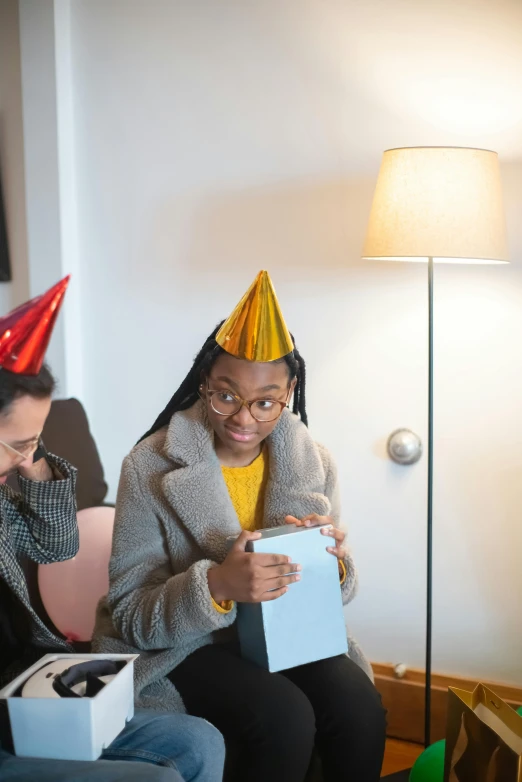 a couple of people that are sitting on a couch, by Nina Hamnett, shutterstock contest winner, party hats, adut akech, at a birthday party, alexandria ocasio cortez