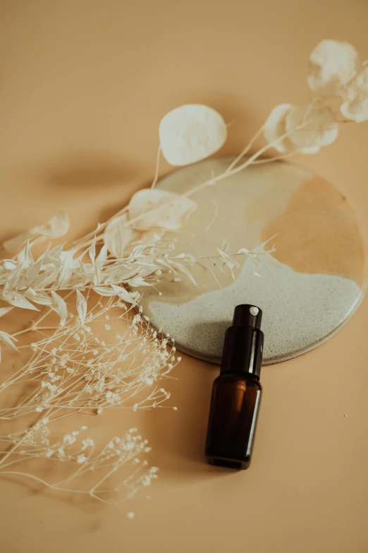 a bottle of essential oil next to some flowers, unsplash, conceptual art, muted brown, thumbnail, lacquer on canvas, handcrafted