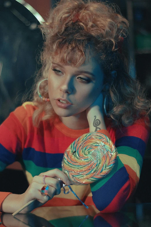 a woman sitting at a table with a lollipop, an album cover, inspired by Elsa Bleda, trending on pexels, renaissance, curly bangs, sydney sweeney, rainbow, candy canes