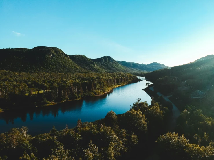 a river running through a lush green valley, by Jesper Knudsen, pexels contest winner, hurufiyya, quebec, ultrawide angle cinematic view, evening sunlight, blue