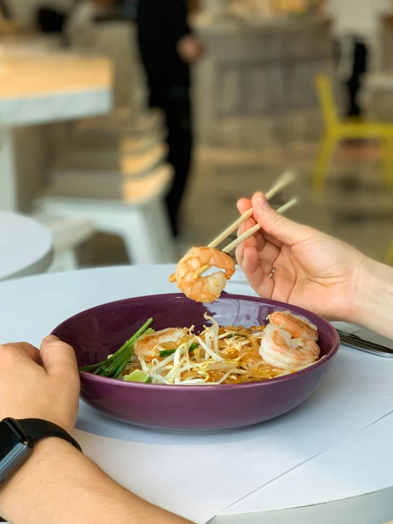 a person eating a bowl of food with chopsticks, food court, on a plate