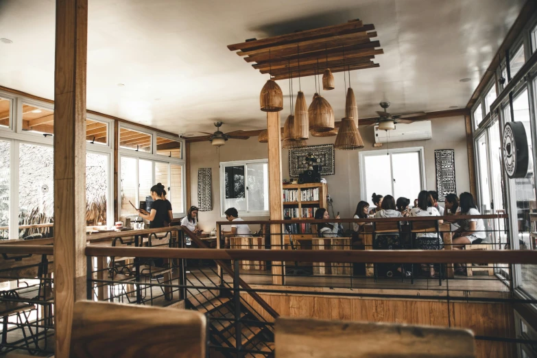 a group of people sitting at tables in a restaurant, pexels contest winner, wooden interior, fan favorite, wooden desks with books, brown and white color scheme