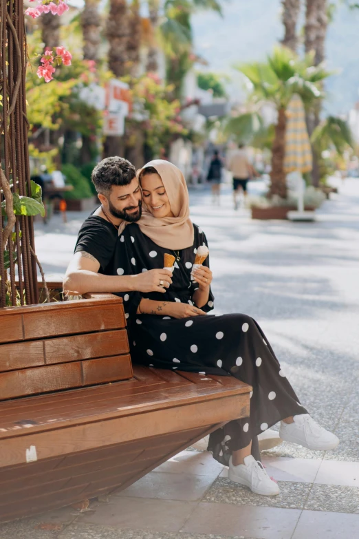 a man and a woman sitting on a wooden bench, pexels contest winner, hurufiyya, embracing, middle eastern, spotted, casually dressed