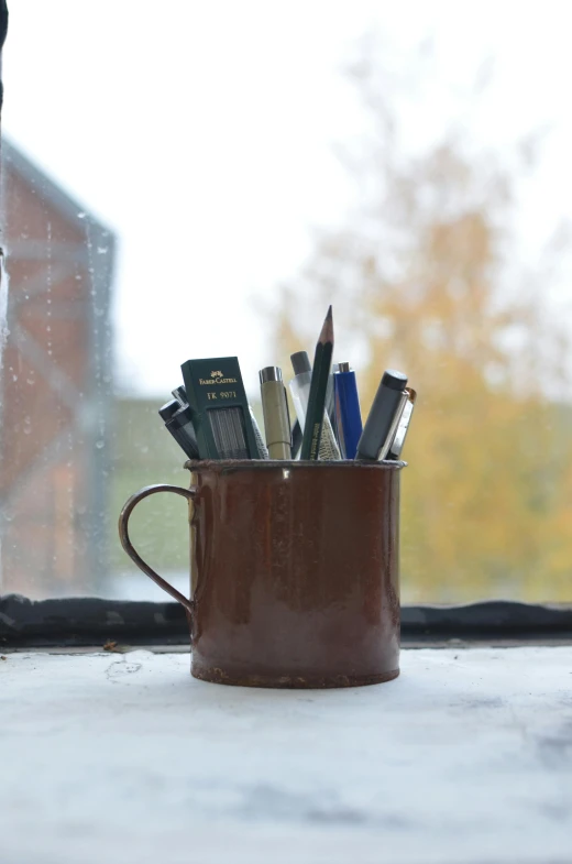 a cup filled with pens sitting on top of a window sill, brown, tin can, ready to model, iconic scene