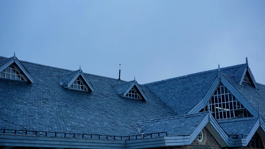 a large building with a clock on top of it, an album cover, by Carey Morris, pexels contest winner, roofing tiles texture, blue gray, beautiful low light, panoramic shot