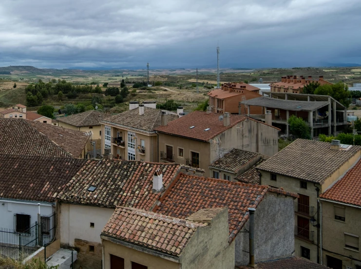 a view of a town from the top of a hill, a portrait, inspired by Modest Urgell, pexels contest winner, romanesque, overcast sky, square, rural, depressing