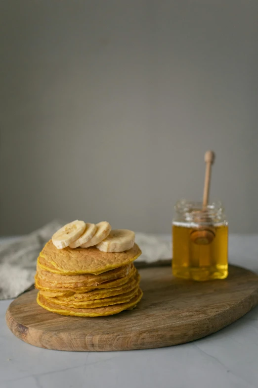 a stack of pancakes sitting on top of a wooden cutting board, a portrait, pexels, jar of honey, banana, crisp image, dwell