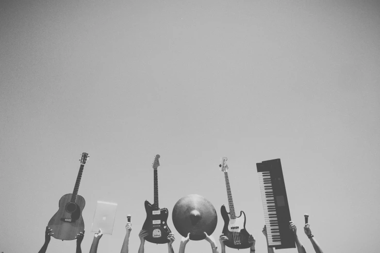 a group of people holding up guitars and a ball, a black and white photo, by Karl Buesgen, unsplash, assemblage, cloudless sky, pianos, frequency indie album cover, miscellaneous objects