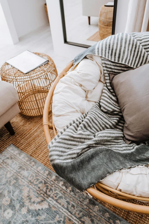 a chair sitting in a living room next to a window, inspired by Constantin Hansen, unsplash contest winner, curled up under the covers, wicker art, striped, birdseye view