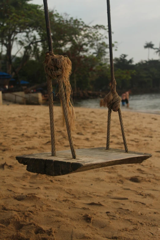 a wooden swing sitting on top of a sandy beach, as well as scratches, obunga, slide show, multiple stories