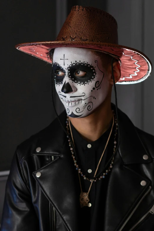 a man wearing a sugar skull mask and a leather jacket, an album cover, inspired by Byron Galvez, trending on pexels, he is wearing a hat, traditional makeup, basquiat, ( ( ( skeleton ) ) )