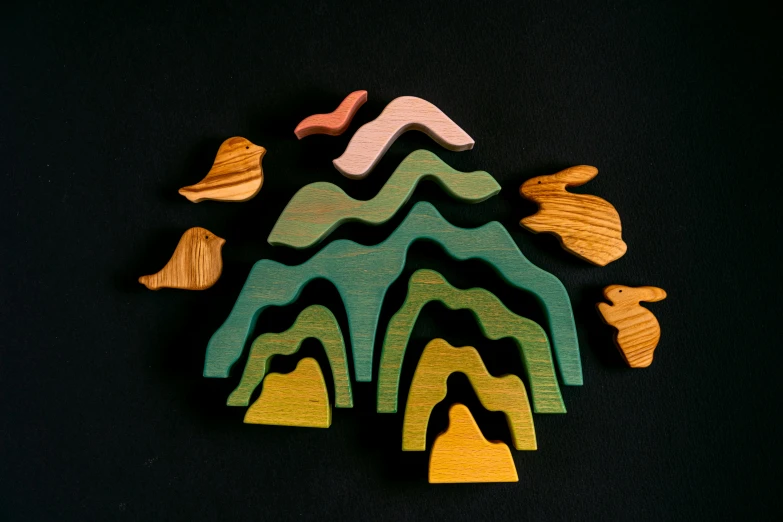 a group of wooden toys sitting on top of a black surface, inspired by Jean Arp, unsplash, land art, island with cave, mountainous, coloured woodcut, grazing