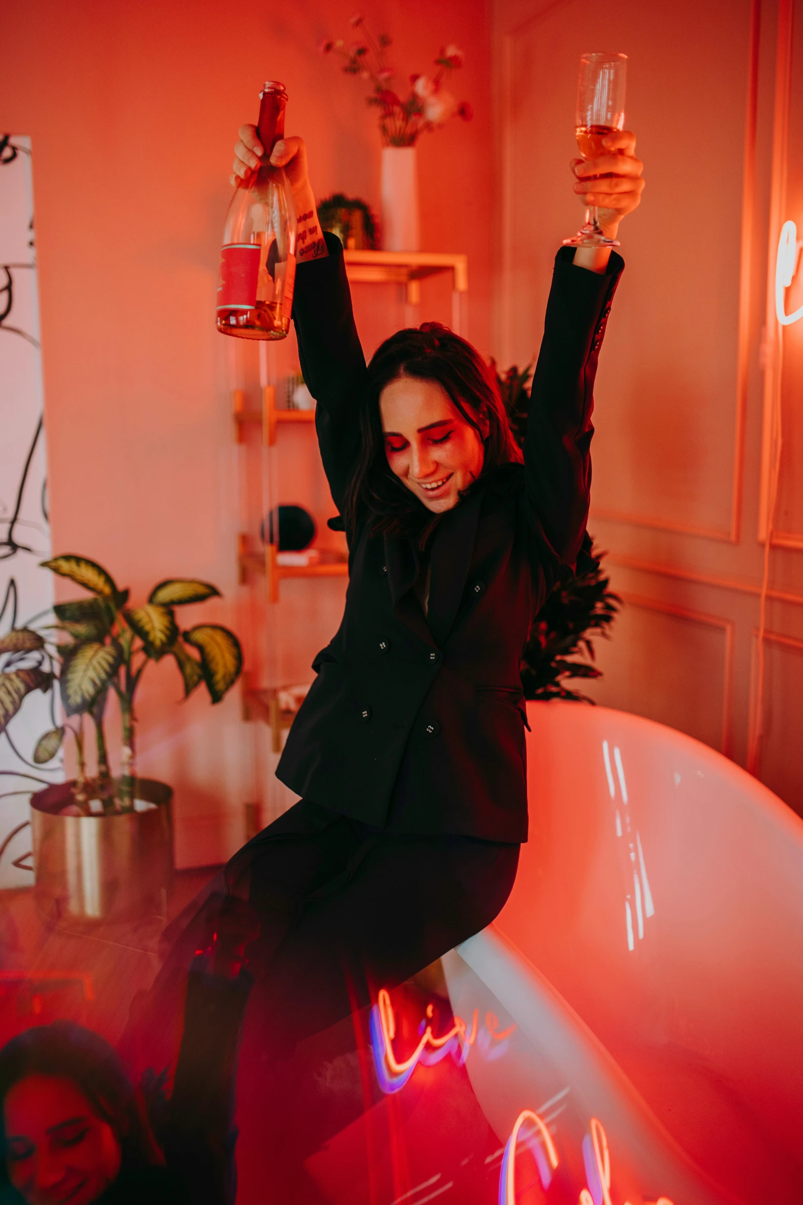 a woman sitting in a bathtub holding a glass of wine, by Julia Pishtar, pexels contest winner, bright trouser suit for a rave, pose(arms up + happy), black and red tuxedo, soft calm warm neon atmosphere