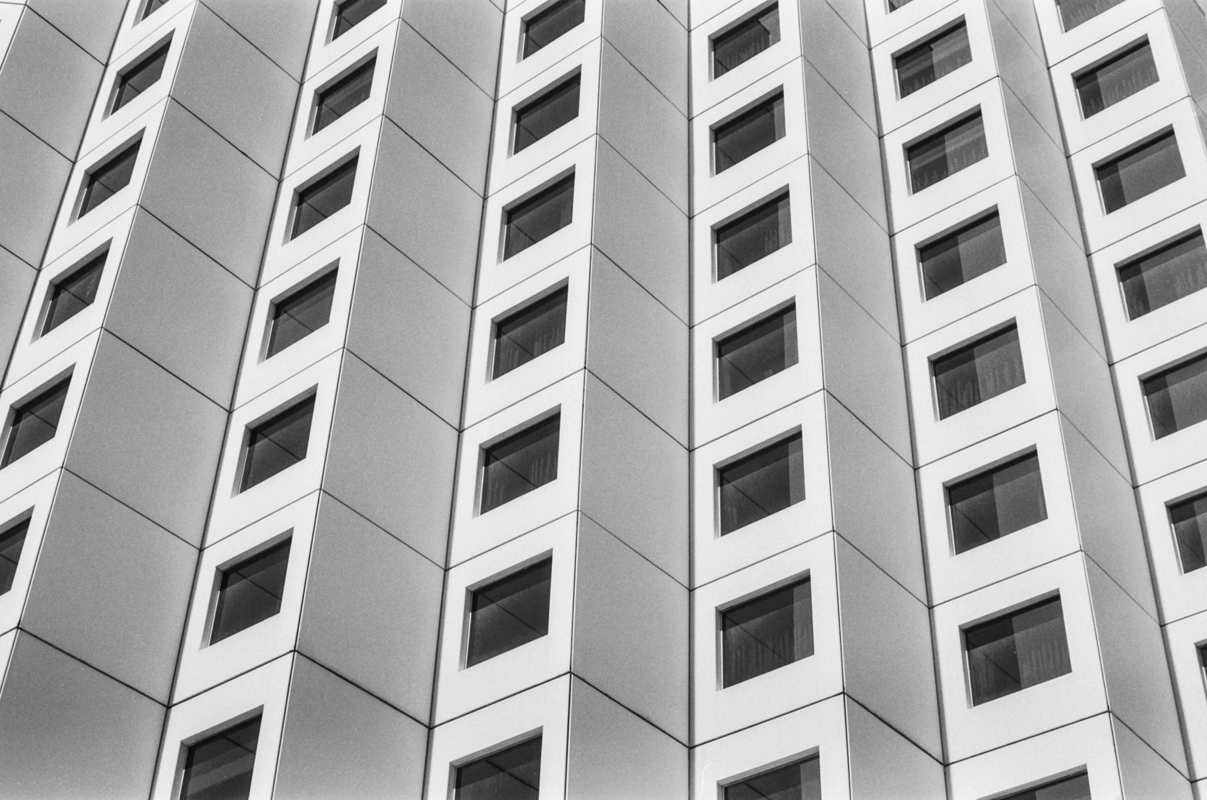 a black and white photo of a tall building, a black and white photo, inspired by Ned M. Seidler, unsplash, house windows, squares, white building, taken in the late 2000s