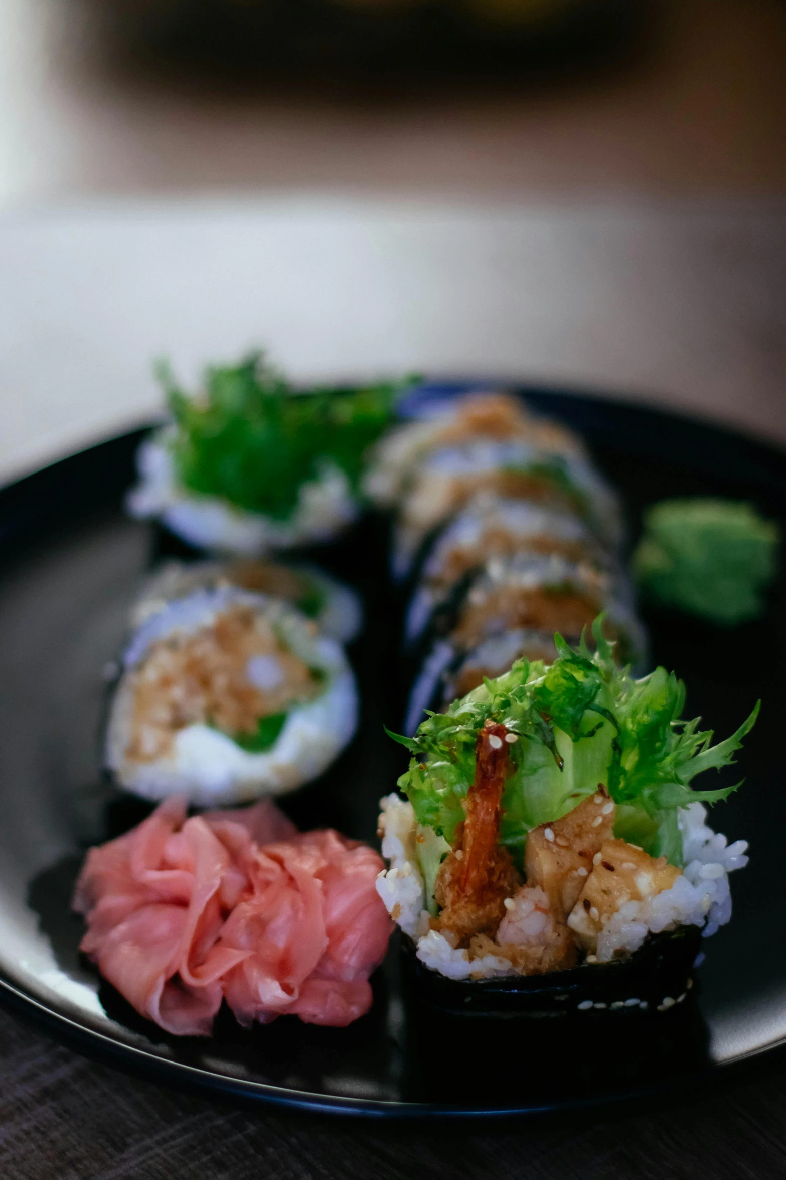 a black plate topped with sushi on top of a wooden table, gills, blue, te pae, 6 pack