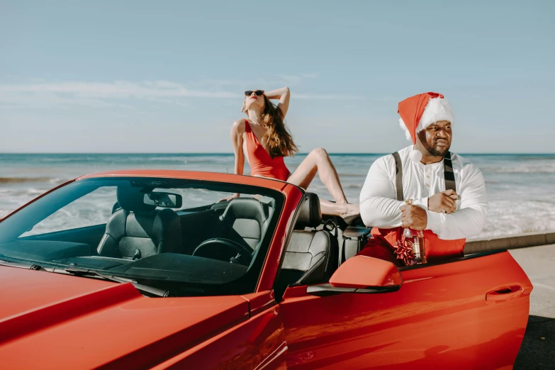 a man standing next to a woman in a red car, an album cover, pexels contest winner, titled'holiday at the beach ', sitting on santa, r&b, champagne commercial