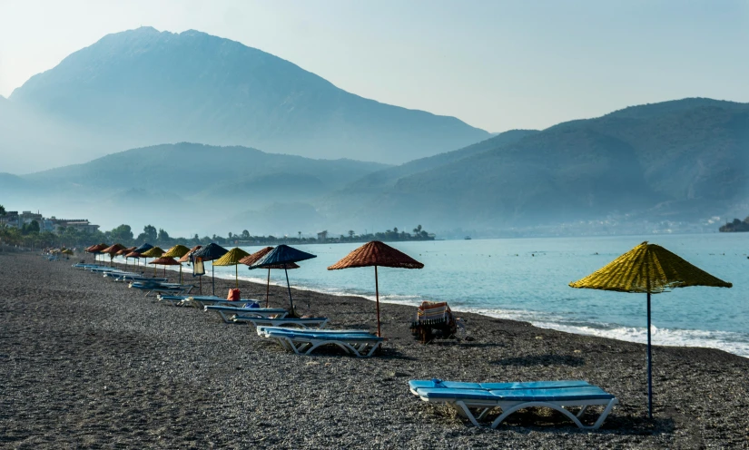 a row of lounge chairs and umbrellas on a beach, by Julia Pishtar, pexels contest winner, mount olympus, mountains and ocean, byzantine, blue themed