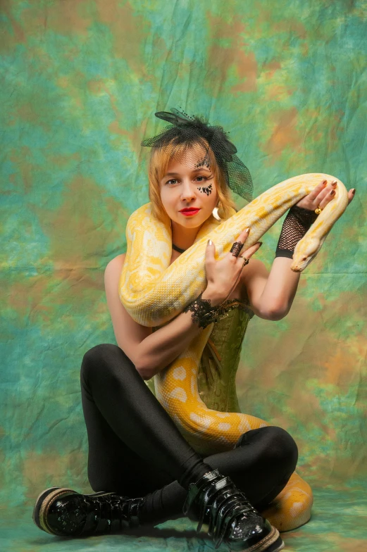 a woman sitting on the ground holding a snake, inspired by Elsa Bleda, renaissance, patricia piccinini, yellow and black, human-animal hybrid, doing a sassy pose