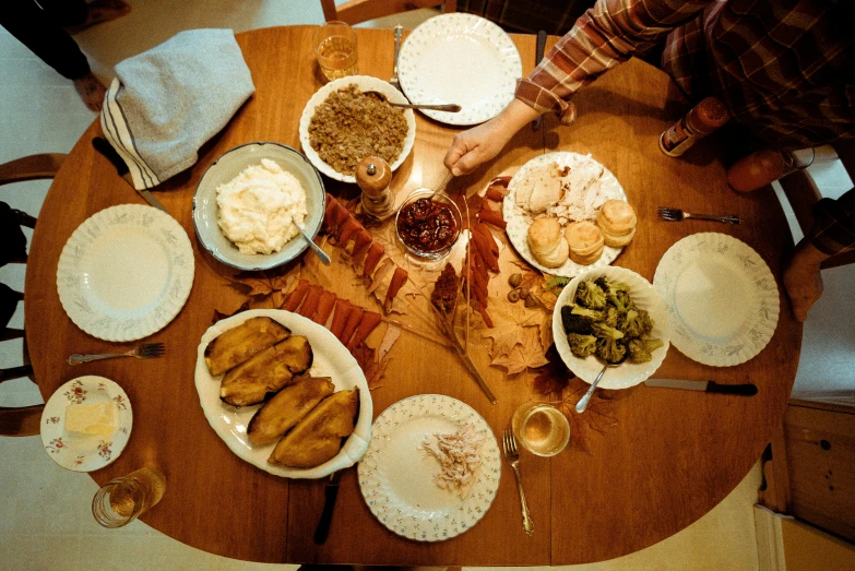 a wooden table topped with plates of food, by Carey Morris, pexels, of a full body, holiday, avatar image, brown