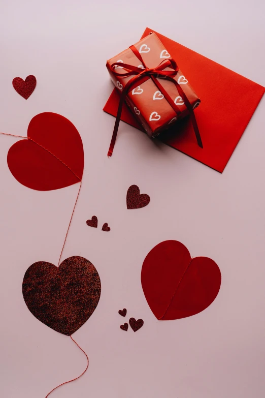 a red envelope sitting on top of a white table, by Valentine Hugo, pexels contest winner, romanticism, several hearts, brown, print, thumbnail