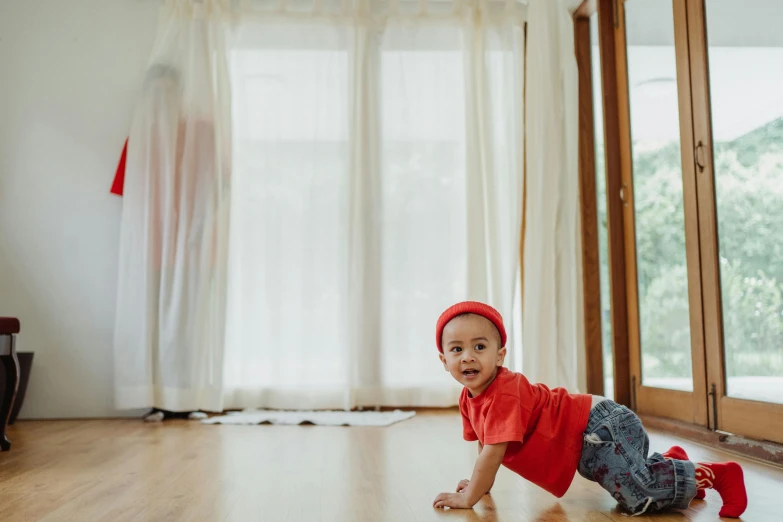 a baby crawling on the floor in a living room, by Basuki Abdullah, pexels contest winner, red shirt brown pants, standing near a window, breakdancing, third trimester