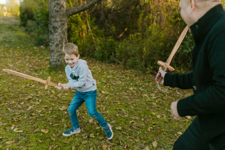 a little boy that is standing in the grass with a bat, sword fighting, older brother vibes, practising her sword staces, holding a wooden staff