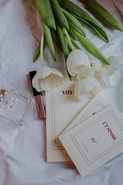 a bouquet of flowers sitting on top of a bed, a still life, by Zofia Stryjenska, pexels contest winner, romanticism, vogue journal cover, all white, perfume, 🎀 🧟 🍓 🧚