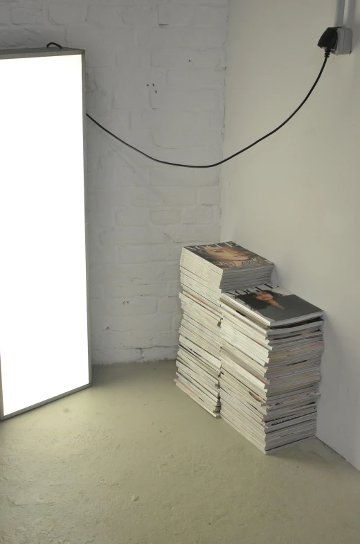 a room with a bunch of books stacked on top of each other, an album cover, postminimalism, exposed wires, low quality photo, white wall complex, studio backlight