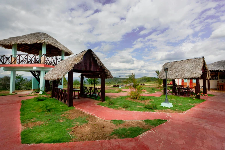 a couple of huts sitting on top of a lush green field, barcelo tomas, exterior photo, eye level view, plaza