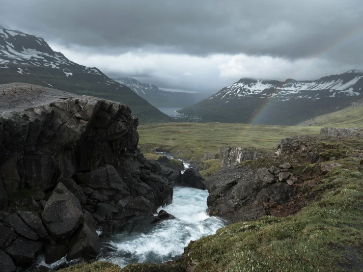 a rainbow shines in the sky over a mountain stream, by Hallsteinn Sigurðsson, pexels contest winner, hurufiyya, rocky roads, grey, overlooking a valley, photo for magazine