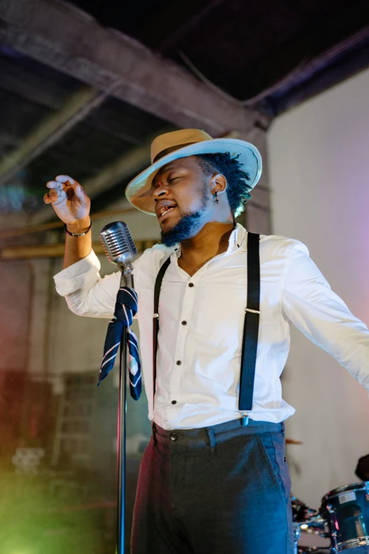 a man in a hat singing into a microphone, an album cover, by Chinwe Chukwuogo-Roy, pexels, happening, 15081959 21121991 01012000 4k, postprocessed), elegantly dressed, low lights