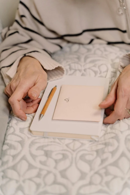 a woman sitting on top of a bed holding a book, a drawing, by Anita Malfatti, trending on unsplash, rose gold heart, holding pencil, wearing a light - pink suit, white sketchbook style