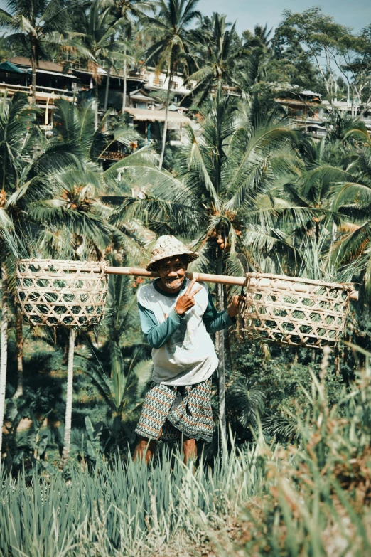 a man holding a stick on top of a lush green field, sumatraism, carrying a tray, in the 1986 vert contest, palmtrees, slightly smiling