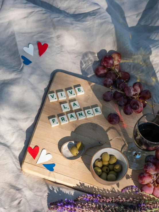 a wooden cutting board sitting on top of a snow covered ground, a picture, french flag, cubes on table, vine, summer vibes