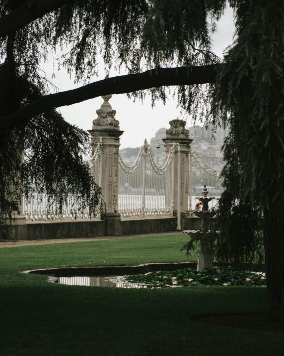 a large tree in a park next to a body of water, a marble sculpture, pexels contest winner, rococo, steel archways, vallejo, lawns, very hazy