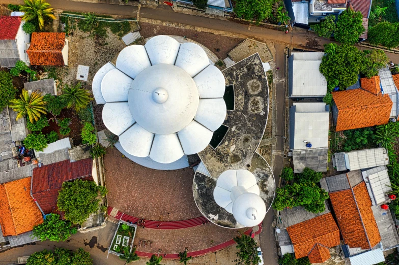 a large white umbrella sitting on top of a lush green field, by Luis Miranda, pexels contest winner, favela spaceship cathedral, aerial view top down, circular towers, brutalism architecture