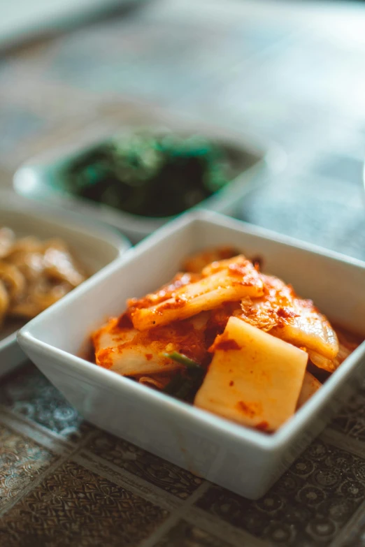 a bowl of food sitting on top of a table, inspired by Kim Myeong-guk, unsplash, square, cheesy, slightly out of focus, sauce