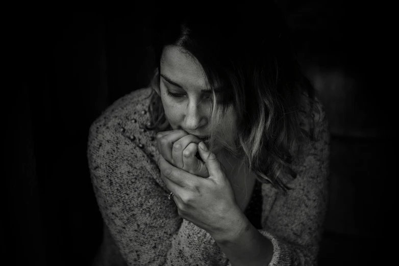 a black and white photo of a woman holding her hand to her face, by Adam Marczyński, pexels, coughing, gloomy and depressed, woman is sitting, low iso