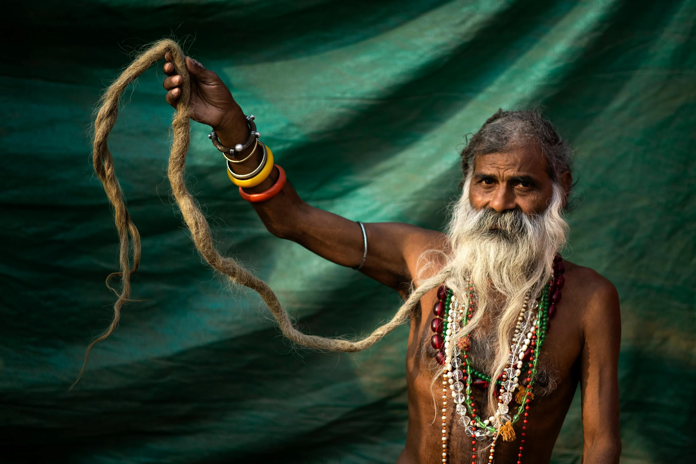 a man with a long white beard holding a rope, pexels contest winner, samikshavad, colourful long hair, wearing loincloth, a black man with long curly hair, oldman with mustach